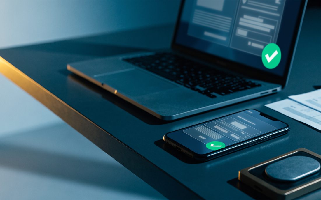 Laptop y teléfono mostrando comprobantes digitales validados, junto a facturas impresas y un token de seguridad