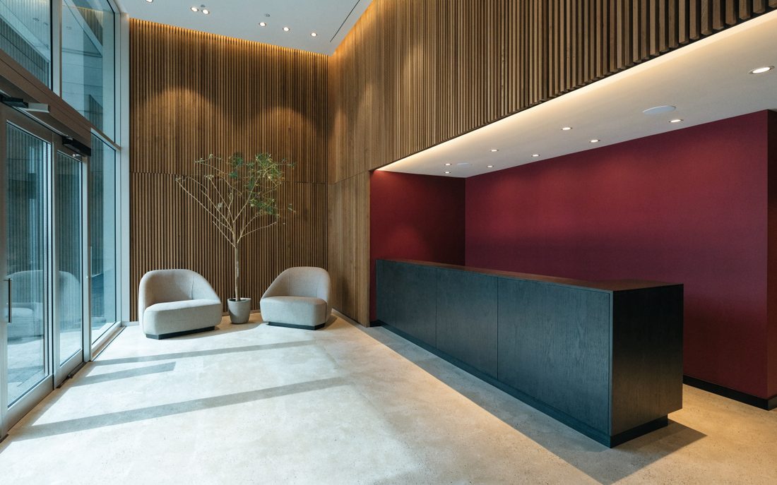 Recepción de un despacho contable con mostrador oscuro, muro vino y entrada de cristal con luz natural